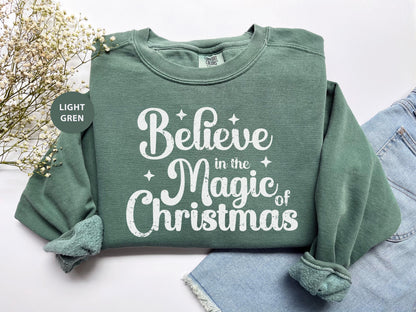 a green sweatshirt that says believe in the magic of christmas