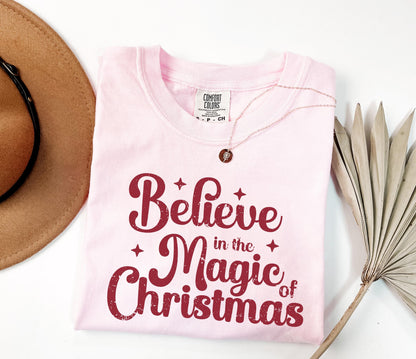 a pink shirt that says believe in the magic of christmas