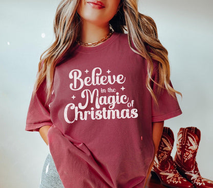 a woman wearing a red believe in the magic of christmas t - shirt
