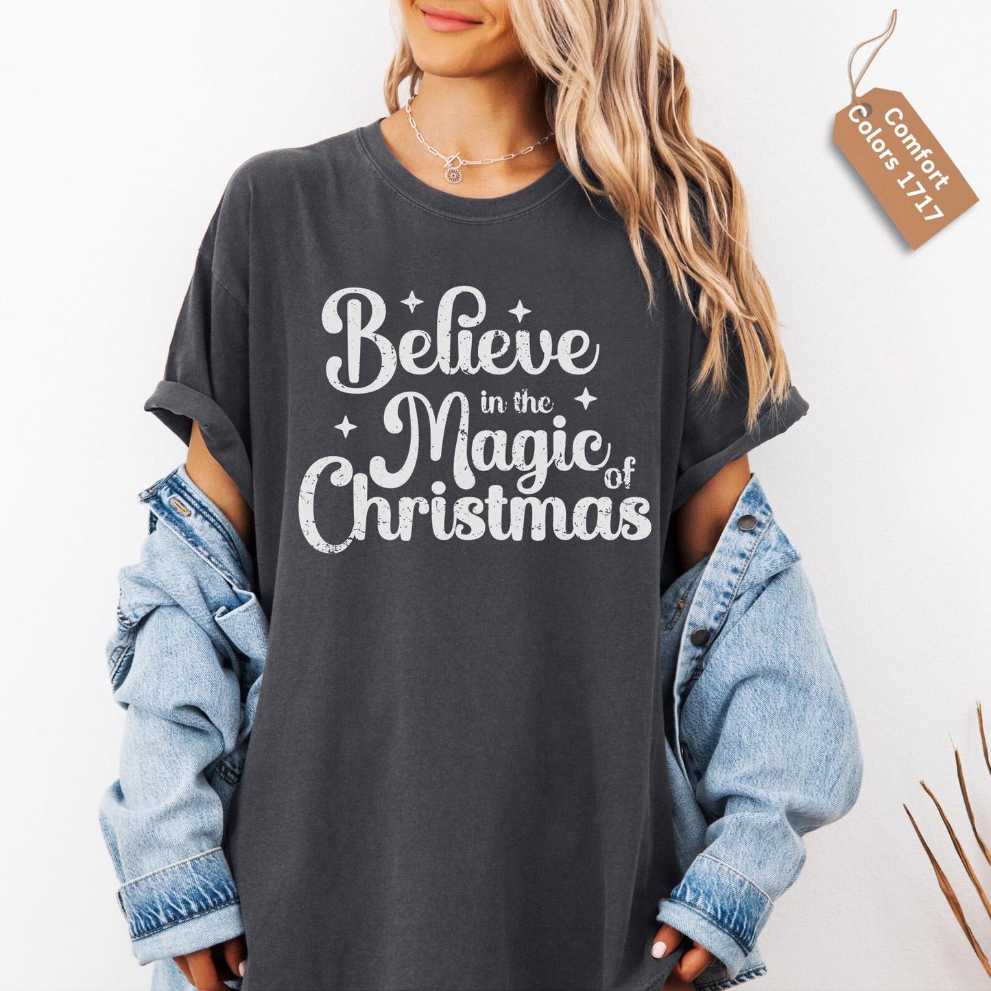 a woman wearing a black believe to the magic of christmas t - shirt