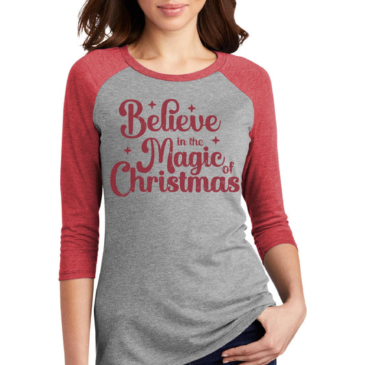 a woman wearing a grey and red shirt with the words believe in the magic of
