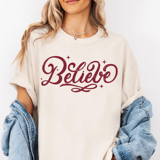 a woman wearing a white sweatshirt with the word believe printed on it
