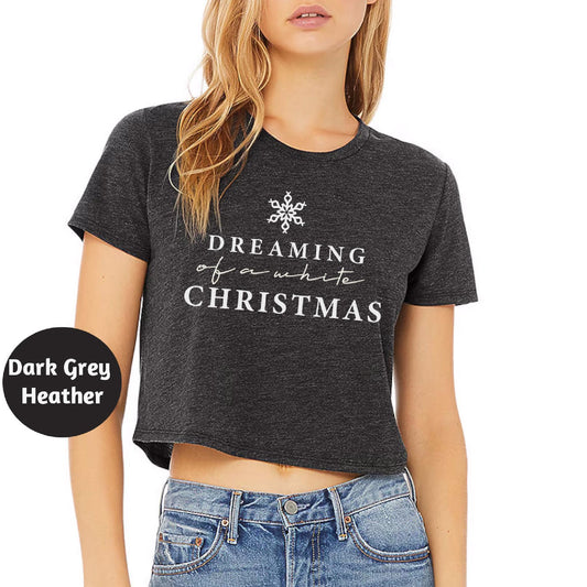 a woman wearing a black crop top with the words dreaming for what christmas is