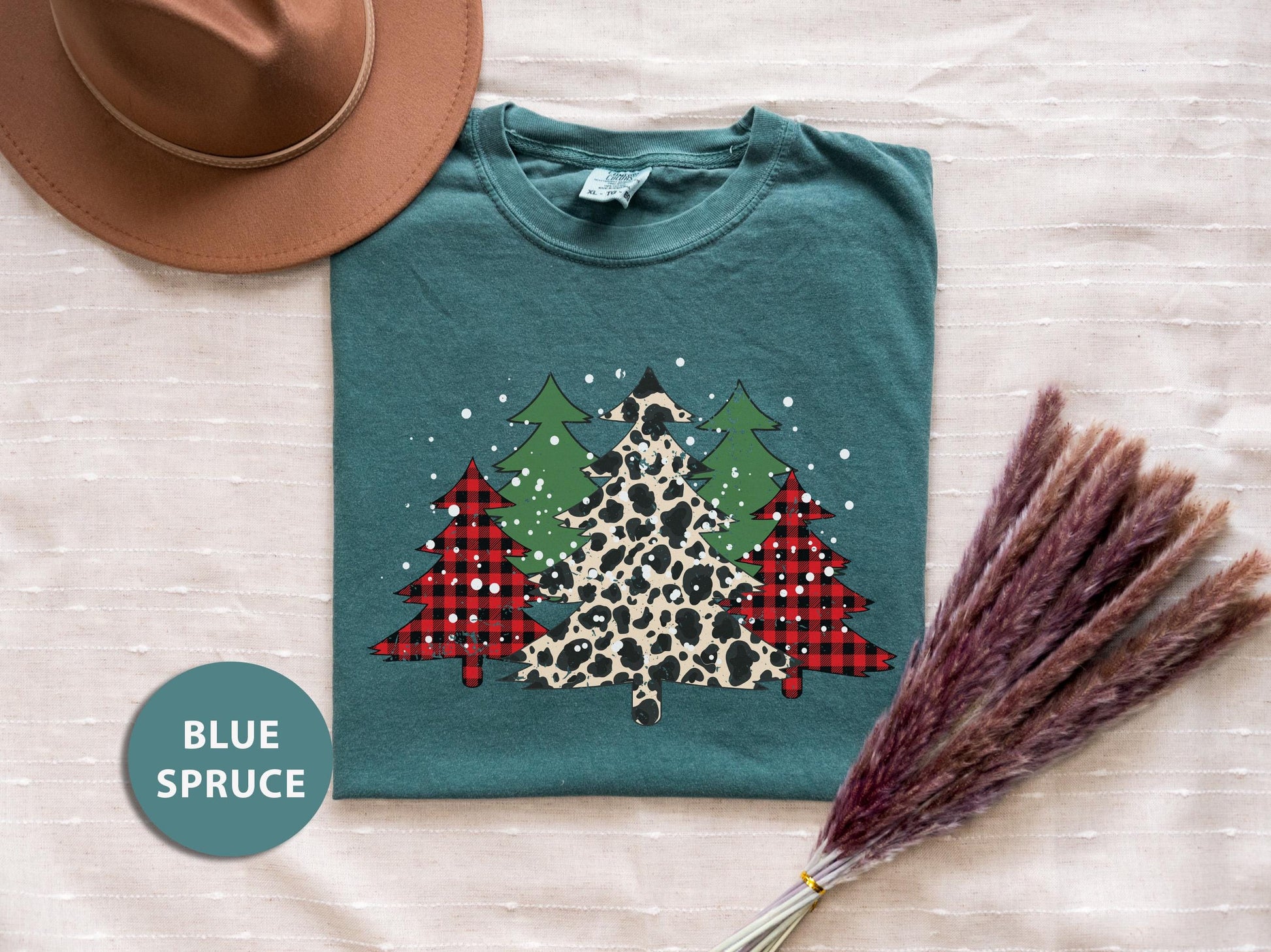 a t - shirt with a christmas tree on it next to a straw hat
