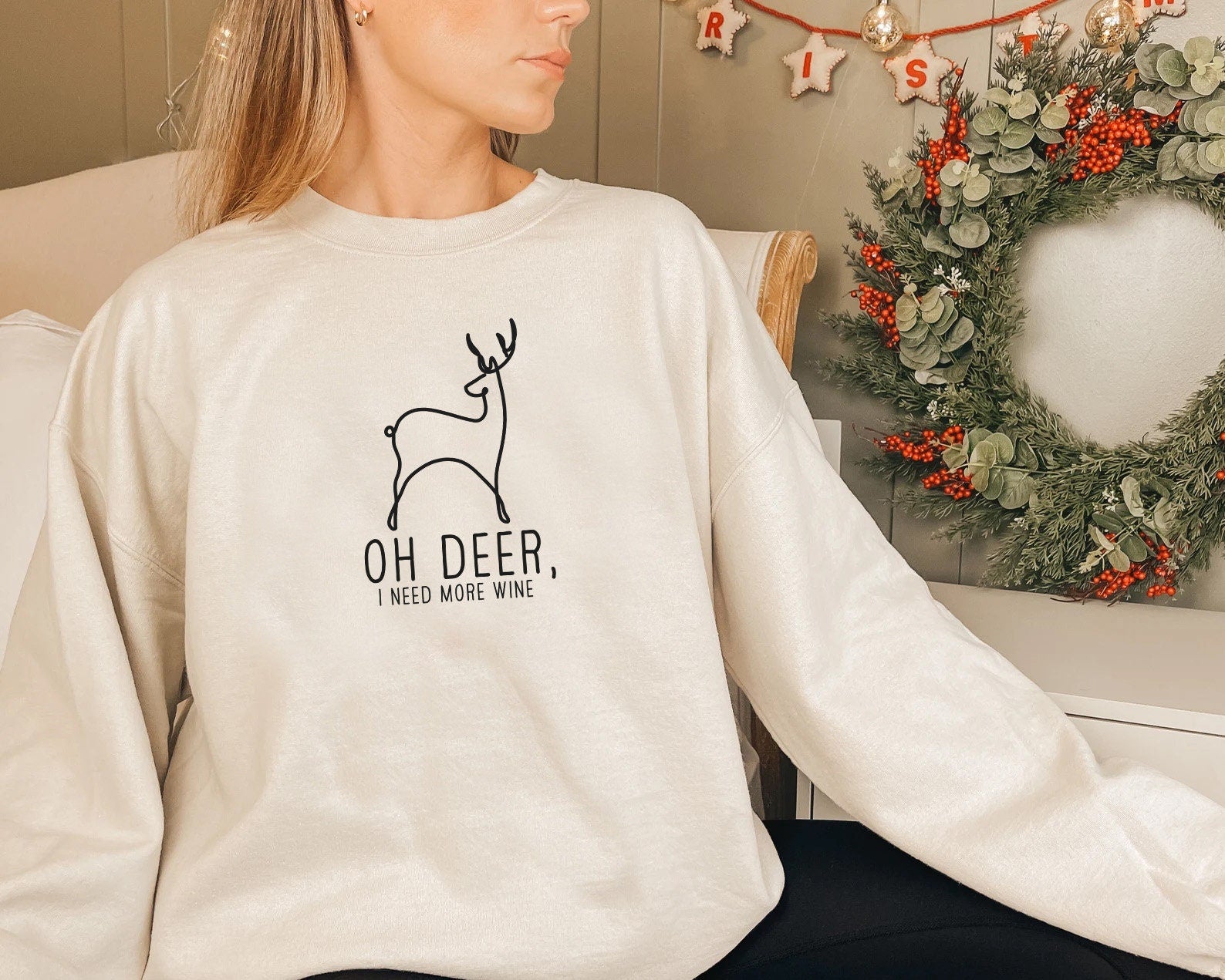 a woman sitting on a chair wearing a sweatshirt with a deer on it