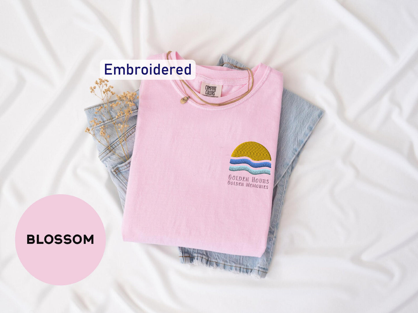 a pink t - shirt with an embroidered sunset on it