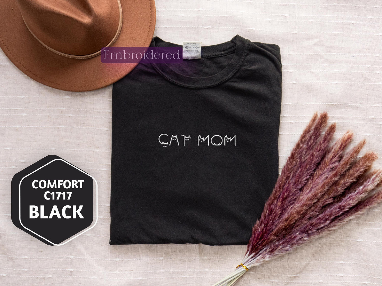 a t - shirt with the word cat mom on it next to a hat and