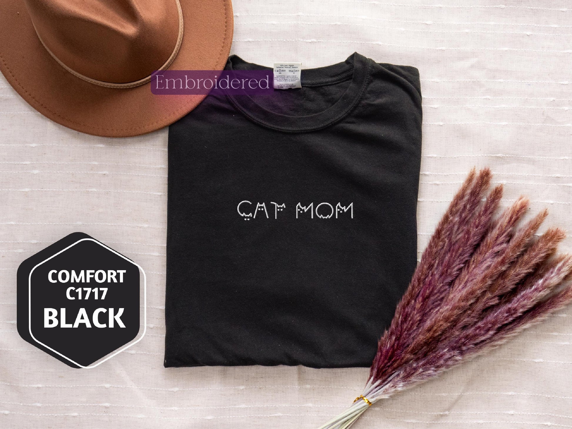 a t - shirt with the word cat mom on it next to a hat and