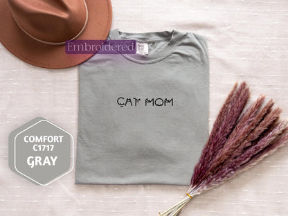 a t - shirt that says cat mom with a hat next to it