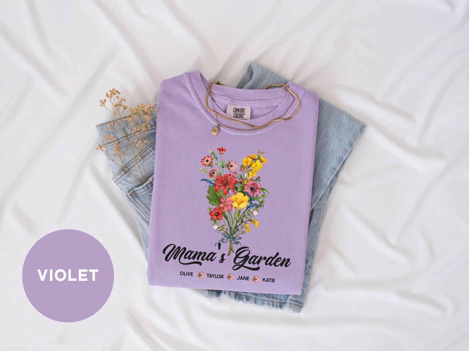 a purple shirt with flowers on it sitting on top of a bed