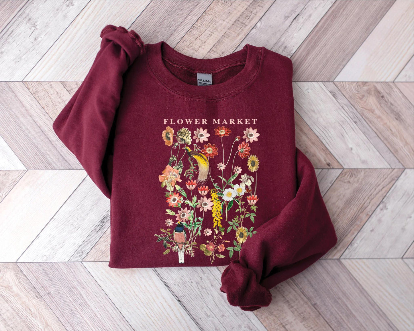 a red flower market sweatshirt laying on a wooden floor