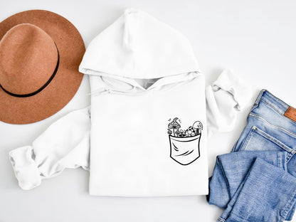 a white hoodie with a pocket full of plants and a hat