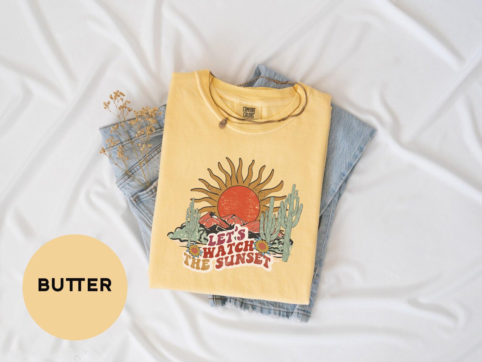 a t - shirt with a sun on it sitting on top of a bed