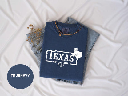 a texas t - shirt laying on top of a pair of jeans