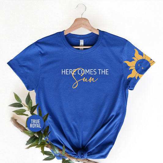 a blue t - shirt with the words here comes the sun on it