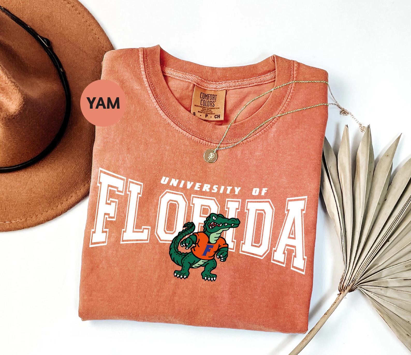 a t - shirt that says university of florida next to a hat