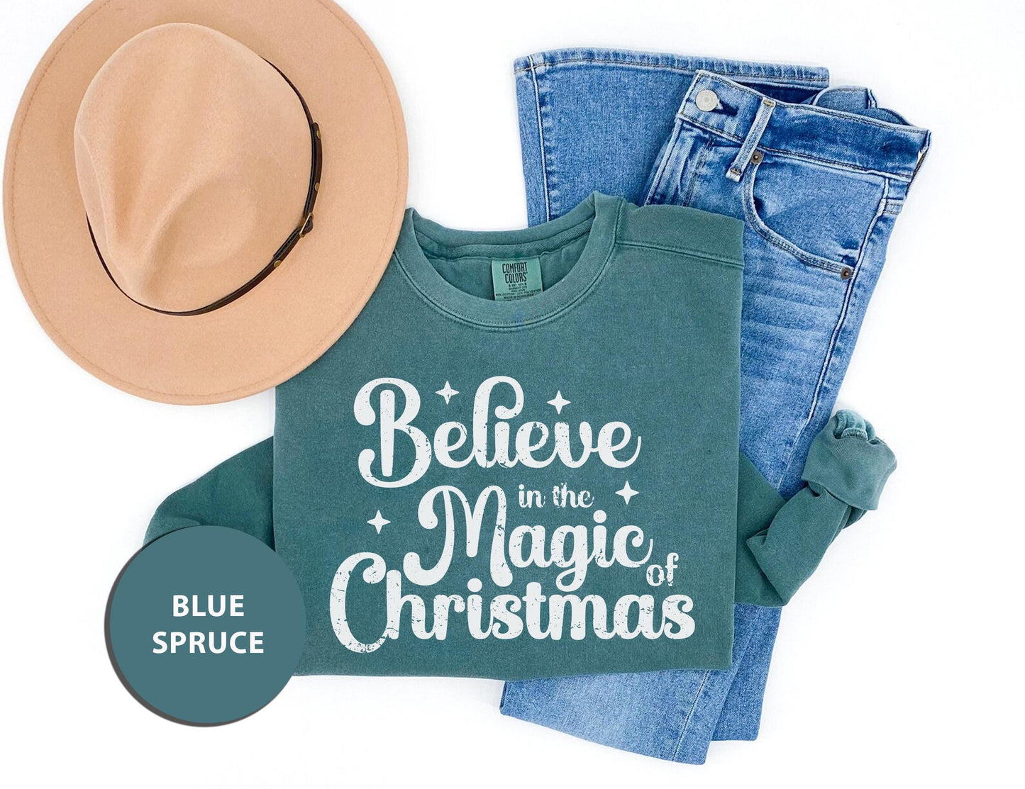 a t - shirt that says believe in the magic of christmas next to a hat