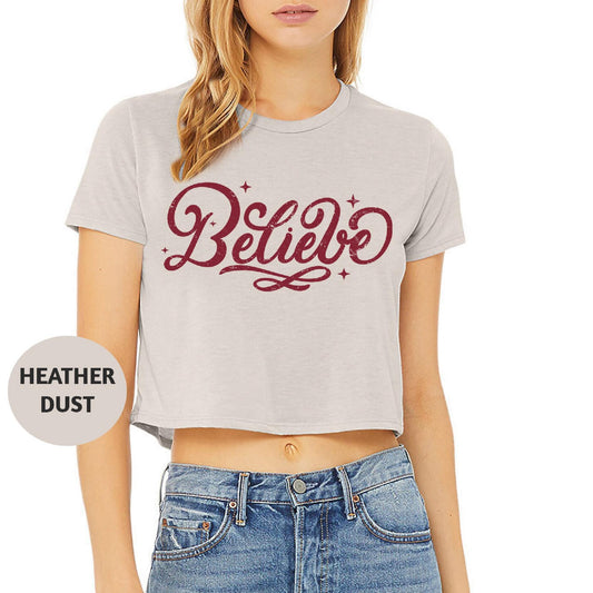 a woman wearing a crop top with the word believe on it