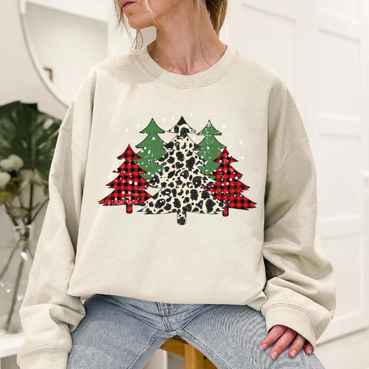 a woman sitting on a stool wearing a leopard print christmas tree sweatshirt